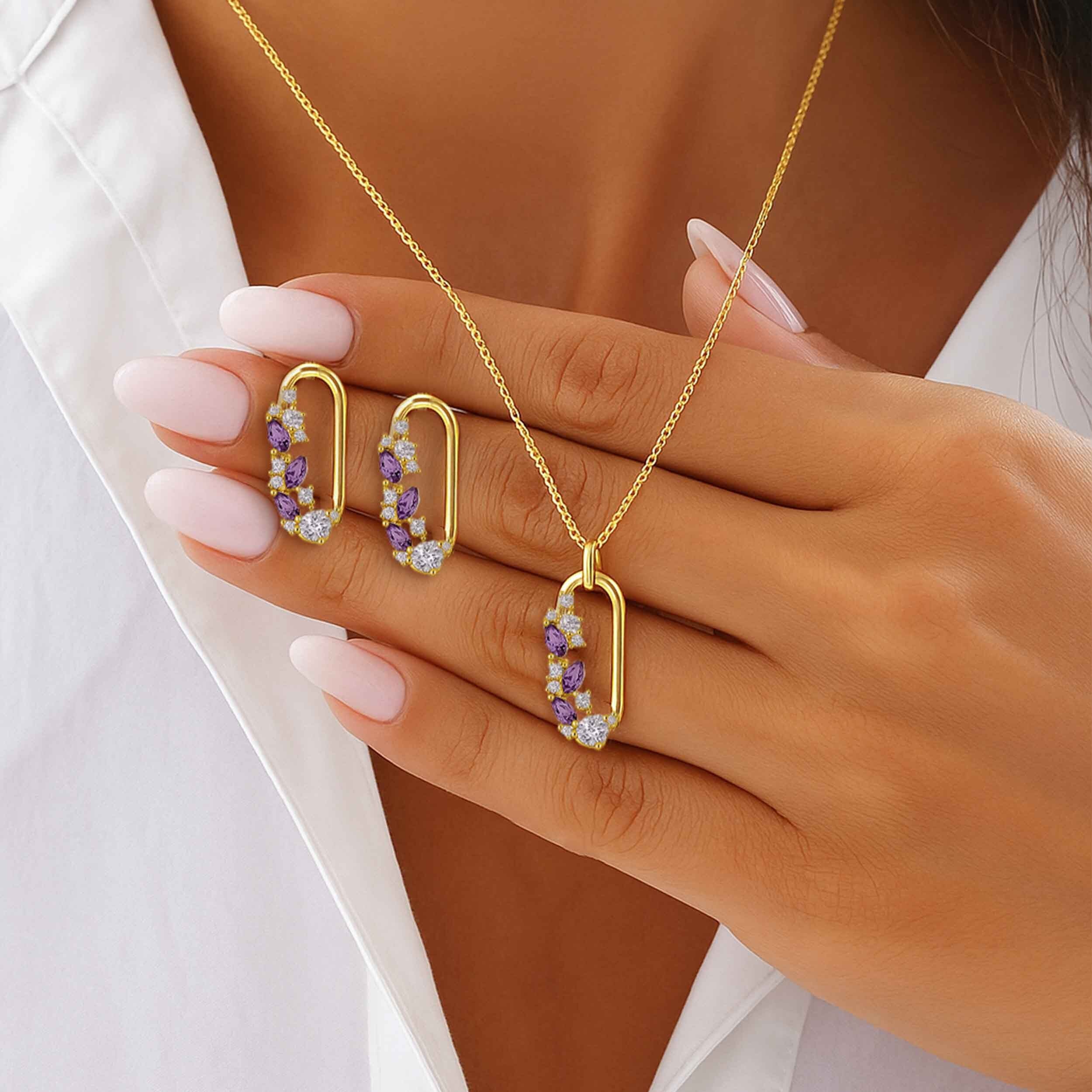 Gold jewelry set with hoop earrings and necklace on a hand against a white background