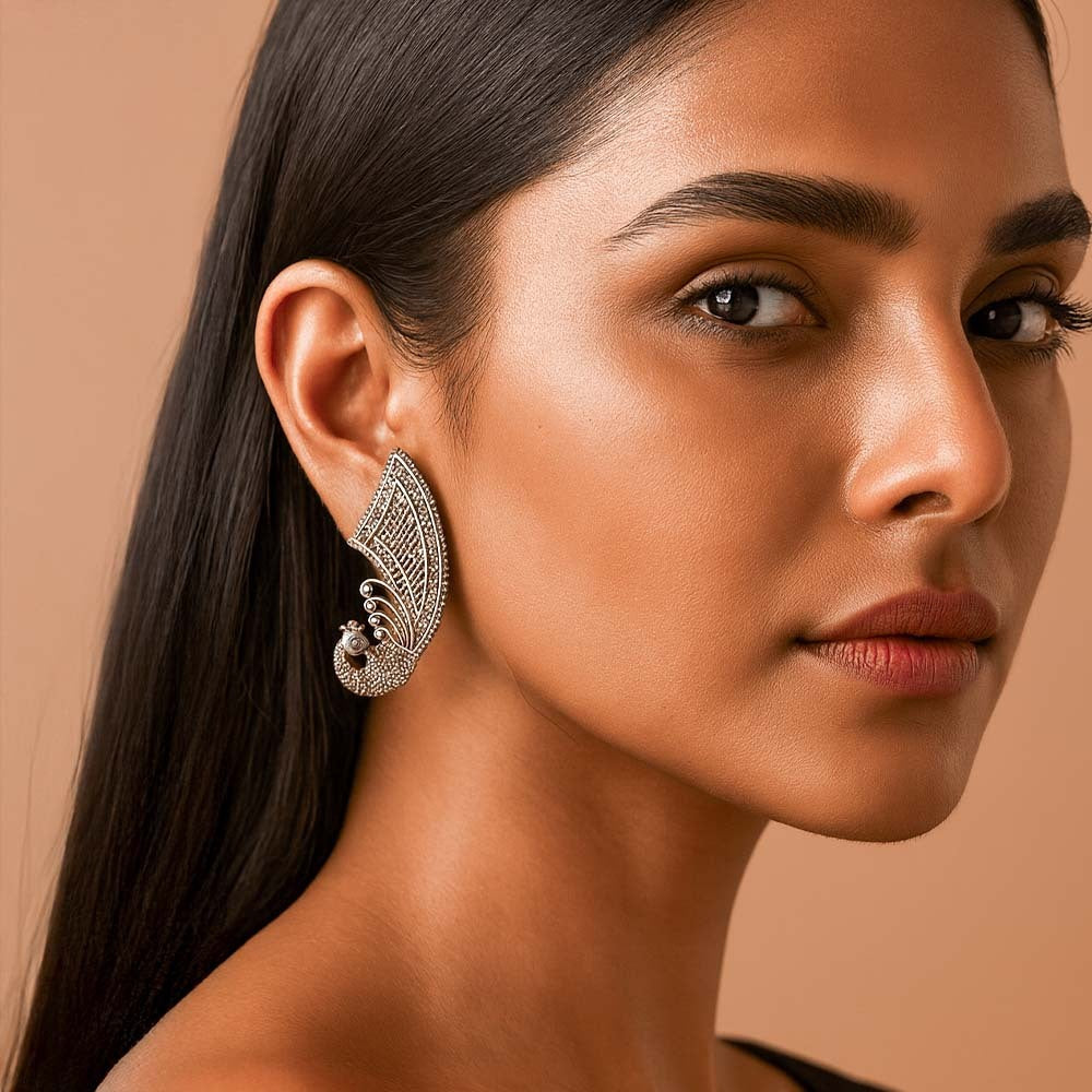 Close-up of a woman wearing an ornate earring against a beige background