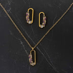 Gold necklace with pendant and matching earrings on a dark marble surface