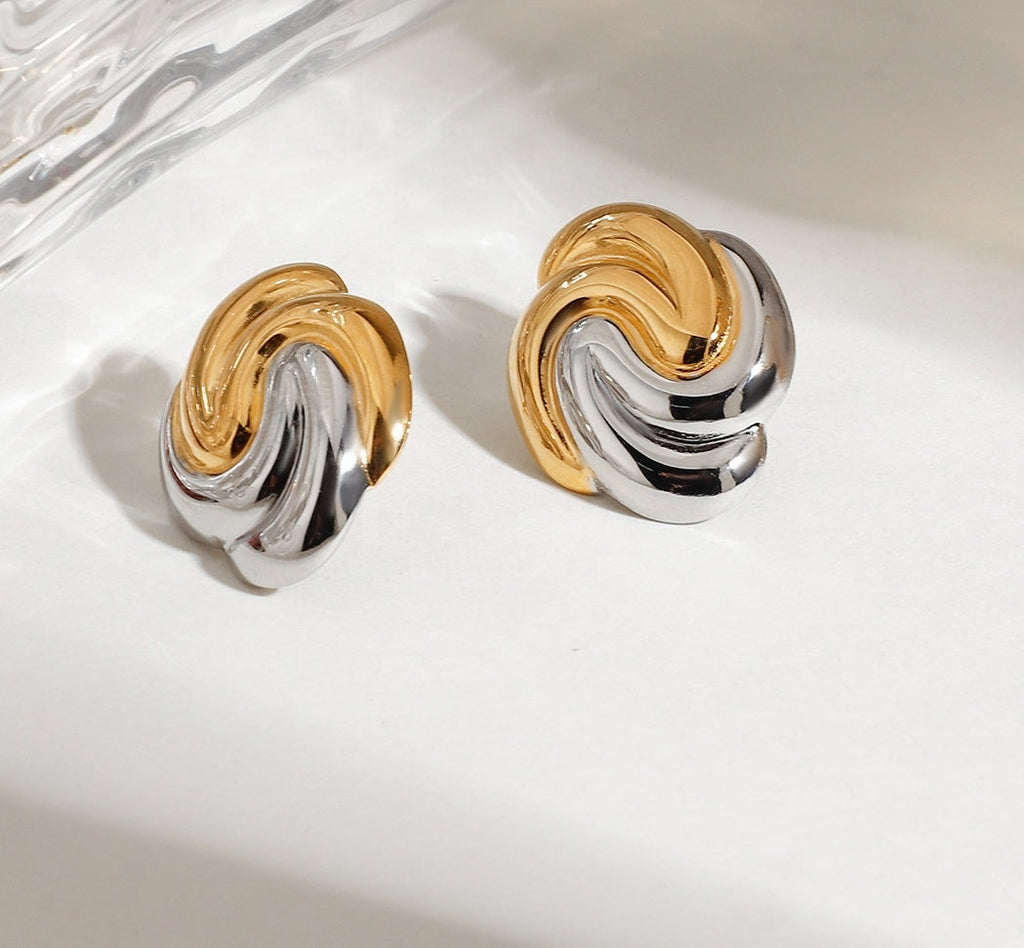 Pair of gold and silver earrings on a marble surface
