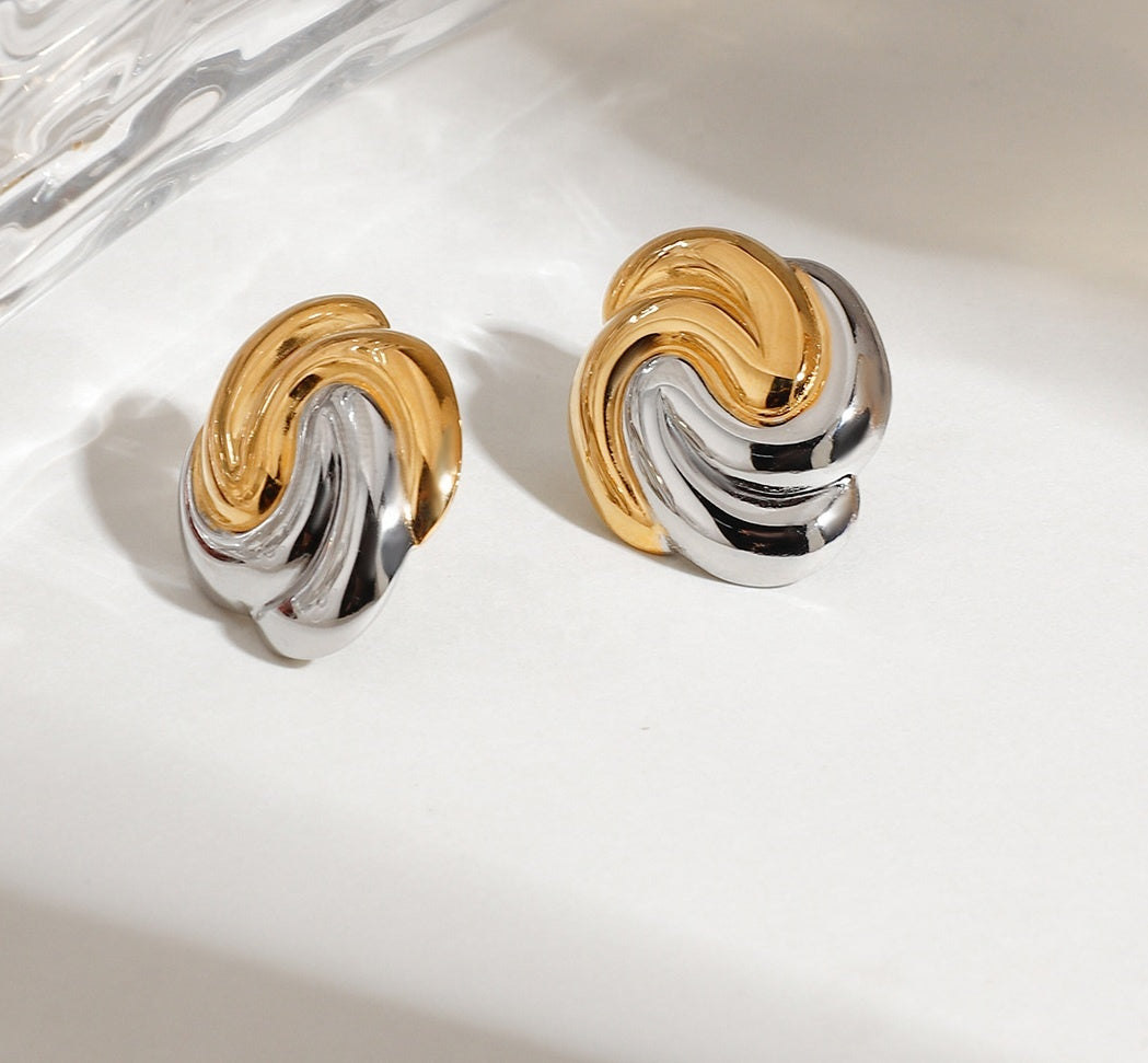 Pair of gold and silver earrings on a marble surface