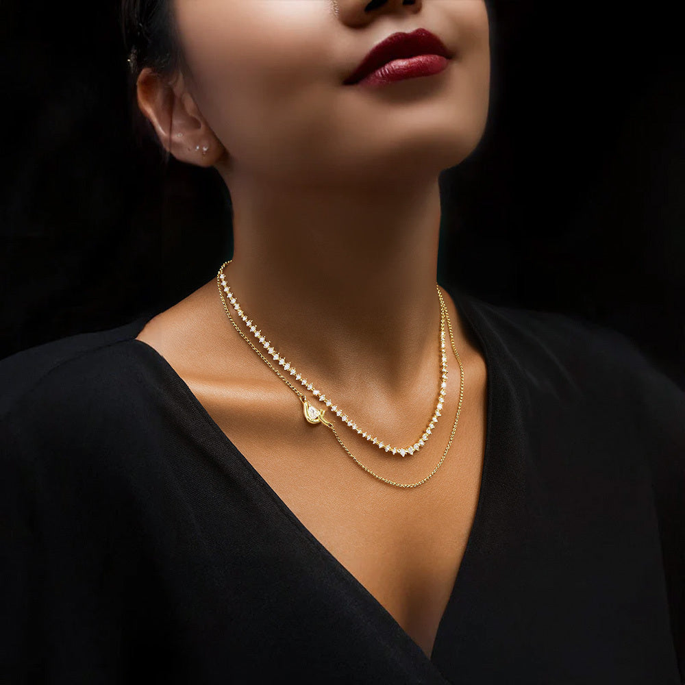 Shop this two-layer gold necklace featuring a sleek pear-cut pendant and a delicate chain of sparkling cubic zirconia stones. A perfect mix of simplicity and shine for everyday wear or special occasions.