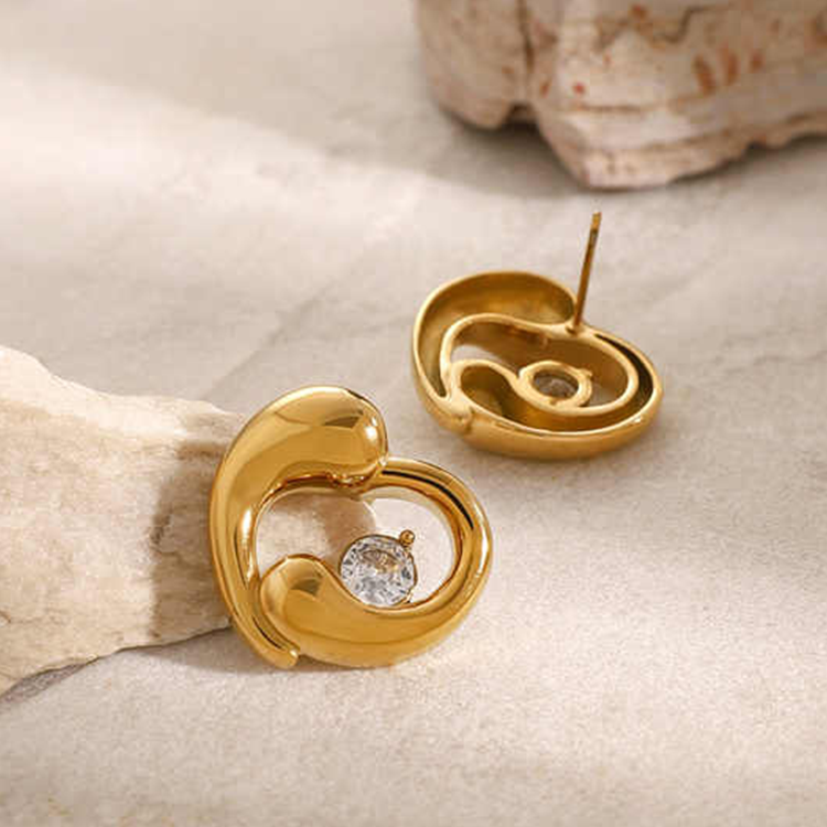 Gold earrings with a central gemstone on a textured beige surface