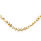 A close-up of a gold tennis necklace featuring round-cut diamonds in a symmetrical prong setting.