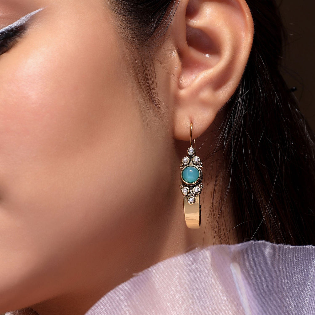 gold earring with a turquoise gemstone.