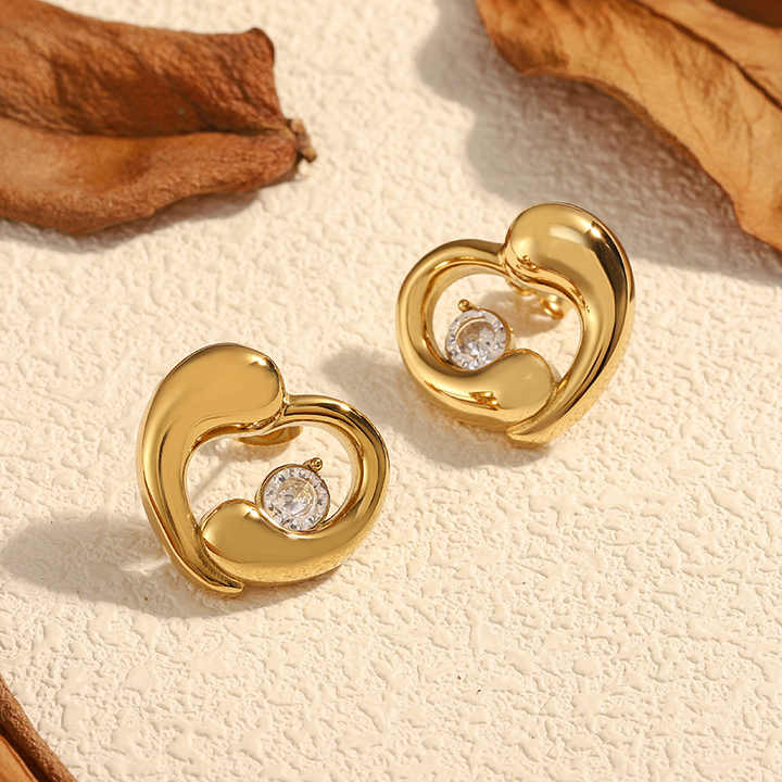 Gold earrings with diamond accents on a textured beige surface
